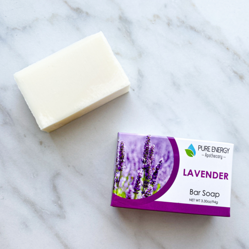 Bar of soap next to its packaging on a marble surface