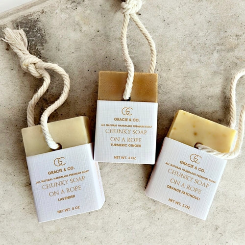 Three bars of Gracie & Co. chunky soap on a rope on a textured surface.