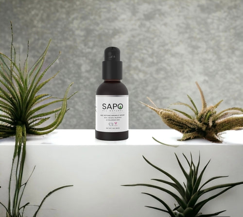 SAPO skincare bottle on a white surface with plants in the background